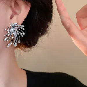Close-up of elegant silver fireworks stud earrings with sparkling zircons and pearls.