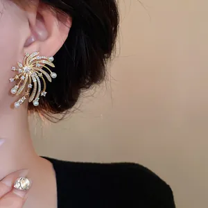 Detailed view of an elegant golden firework stud earring featuring zircons and white pearls