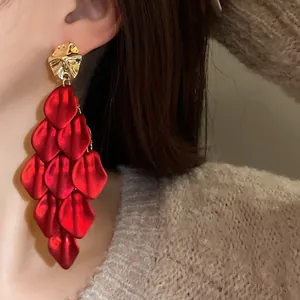 Macro view of elegant red petal tassel earrings featuring gold hammered metal studs