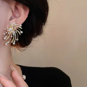 Close-up detail of elegant gold firework zircon and pearl stud earrings worn on model's ear