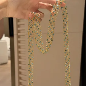 Macro detail of long hollow gold mesh sweater necklace with radiant blue glass beads