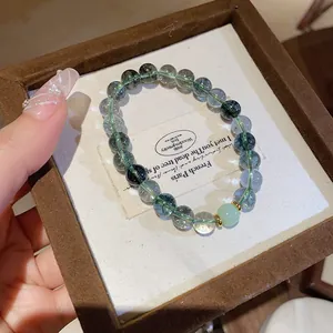 Close-up of green phantom crystal beaded bracelet with gold accents on velvet box.