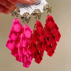Close-up of vibrant pink and red petal tassel earrings with gold textured metal tops.