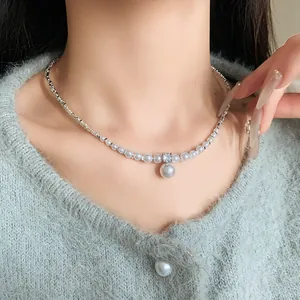 Close-up view of a French style zircon and artificial pearl necklace on a model neck