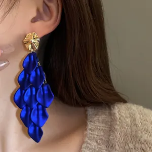 Detailed close-up showing the texture of royal blue satin petal tassel earrings on model
