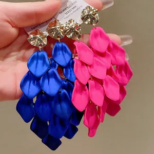 Close-up detail of vibrant pink and blue petal-shaped tassel earrings with gold studs.