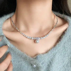 Close-up of an elegant zircon faux pearl necklace with silver beads on a female model's neck.
