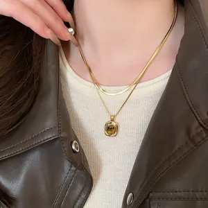 Primo piano di collana placcata oro a due strati con pendente quadrato in occhio di tigre.