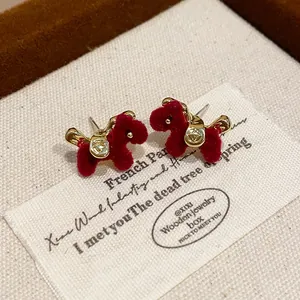 Macro view of retro red flocked horse stud earrings with exquisite gold metal saddle