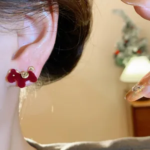 Detailed view of a red flocked horse earring with a delicate gold rose on an ear.