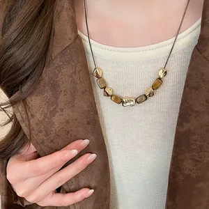 Dettaglio di collana vintage placcata oro con pietre occhio di tigre marrone su modella.