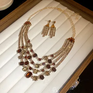 Vintage multi-layer necklace and earrings set with amber rhinestones on a display tray