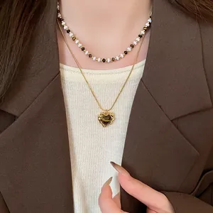 Primo piano della collana con ciondolo a cuore in occhio di tigre e catena di perle