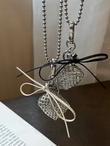 Detailed view of silver beaded necklace featuring black and white bows with crystal hearts.