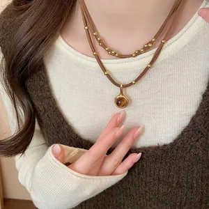 Dettaglio di una collana vintage con pietra occhio di tigre, perline dorate e cordino