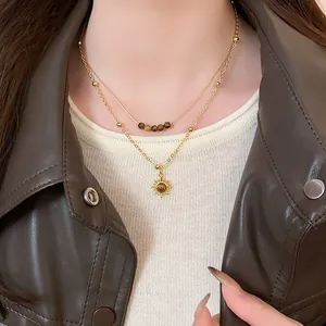 Dettaglio della collana a strati placcata in oro con perle occhio di tigre e pendente sole