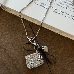 Detailed view of silver ball chain necklace with woven bag, heart charms and black ribbon bow.