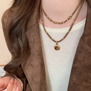 Dettaglio ravvicinato di una collana a due strati in occhio di tigre marrone con perline d'oro.