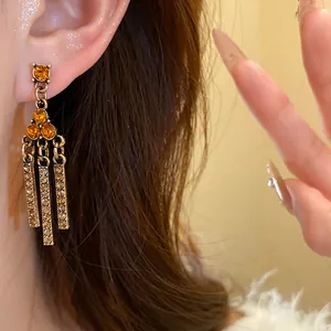 Close-up of vintage bronze earrings featuring amber crystals and elegant rhinestone tassels