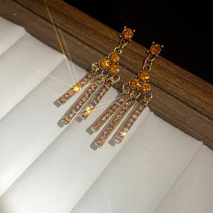 Macro view of vintage gold dangle earrings with amber rhinestones and sparkle effects