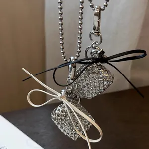 Detailed view of woven heart necklaces featuring elegant black and white bow decorations.
