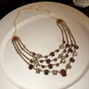 Close-up of multi-layer vintage necklace with amber and clear crystals on white plate