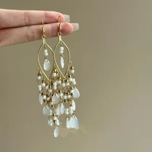 Detailed view of Bohemian gold chandelier earrings with white seed beads and teardrop tassels.