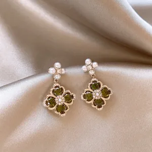Macro detail of vintage style flower drop earrings with green zircon and white pearls