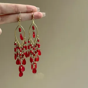 Close-up of vintage Bohemian red glass bead teardrop tassel earrings with elegant gold hooks