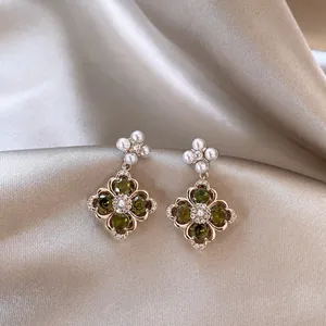 Vintage floral drop earrings with green zircon and pearls on elegant silk background
