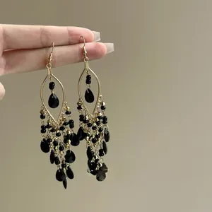 Detail view of Bohemian vintage dangle earrings featuring black glass beads and gold tassels.
