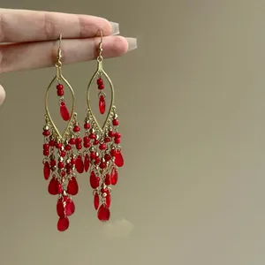 Detail of bohemian red glass bead tassel earrings with golden hook design