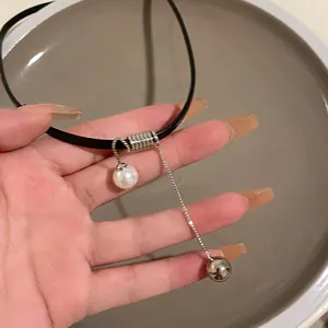 Dettaglio di un girocollo in pelle nera con ciondoli a forma di perla e sfera d'argento