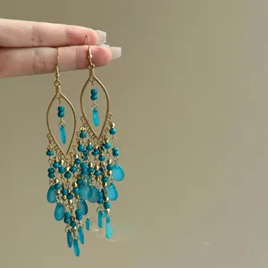 Detail view of Bohemian teardrop tassel earrings featuring turquoise glass beads.