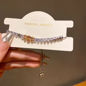 Detail of adjustable tennis bracelet with teardrop zircons in white and champagne