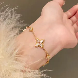 Detailed view of a gold flower bracelet with sparkling teardrop zircons worn on wrist
