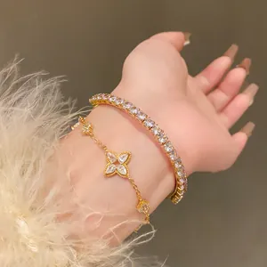 Macro view of elegant gold-tone flower charm bracelet paired with a zircon tennis bracelet