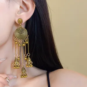 Detailed view of ethnic style vintage gold tassel earrings with bell pendants