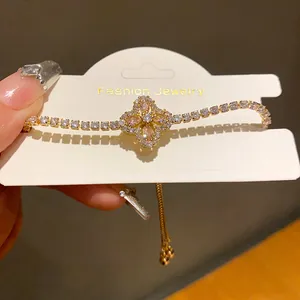 Detailed close-up of a gold-tone luxury bracelet featuring a zircon flower and teardrop petals