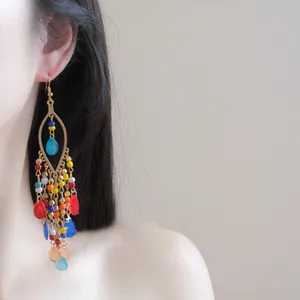 Close-up view of colorful bohemian glass seed bead tassel hook earrings worn by a model