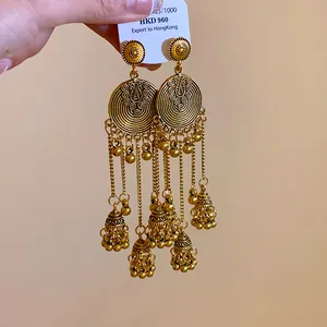 Close-up of ethnic gold tassel earrings with intricate filigree and jhumka bell charms