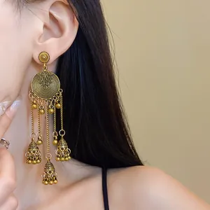Close-up detail of ethnic vintage golden tassel earrings with round plate and bells