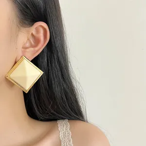 Close-up of elegant cream resin diamond-shaped stud earring with gold-tone frame