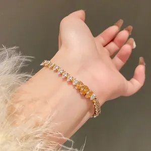 Detailed close-up of a golden bracelet with white and amber waterdrop zircons on wrist