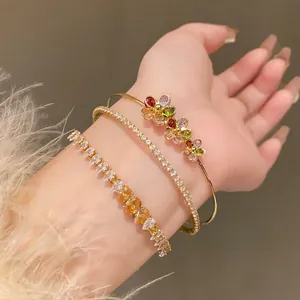 Stackable gold zircon flower and teardrop bracelets shown on wrist detail