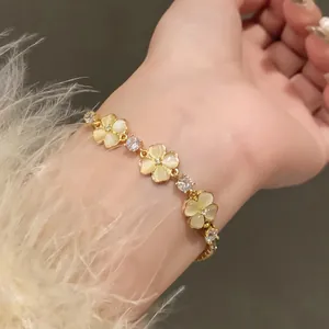 Close-up of an elegant gold flower bracelet with cat-eye stones on a woman's wrist