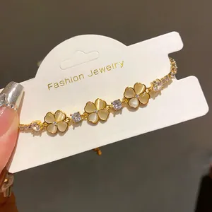 Close-up of gold clover bracelet with cat-eye stones and cubic zirconia on display card