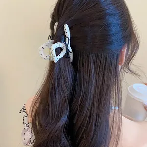Detailed view of a white polka dot bow hair claw clip styled in long dark hair