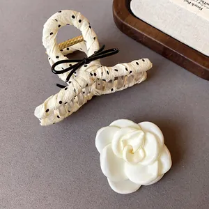 Detailed macro view of French polka dot bow hair claw clip and elegant white camellia flower