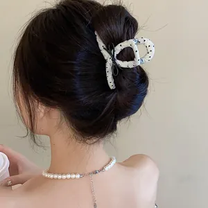 Detailed view of a white polka dot bow hair claw clip used for a French bun hairstyle
